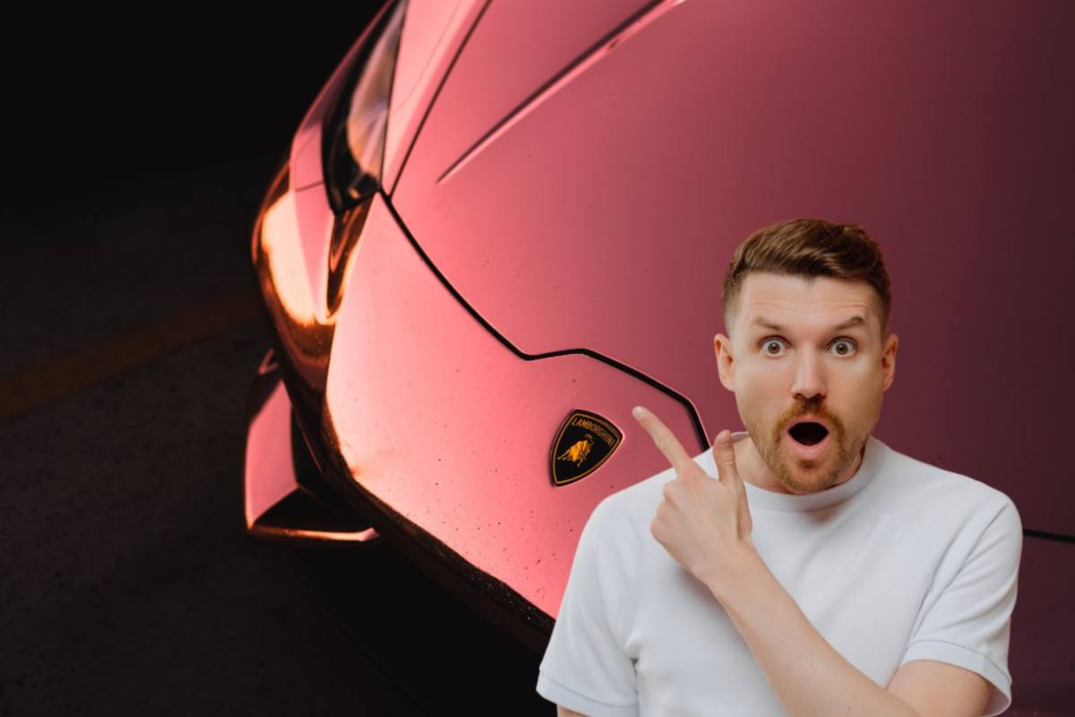 Il cofano di una Lamborghini con lo stemma e un ragazzo a bocca aperta che lo indicata